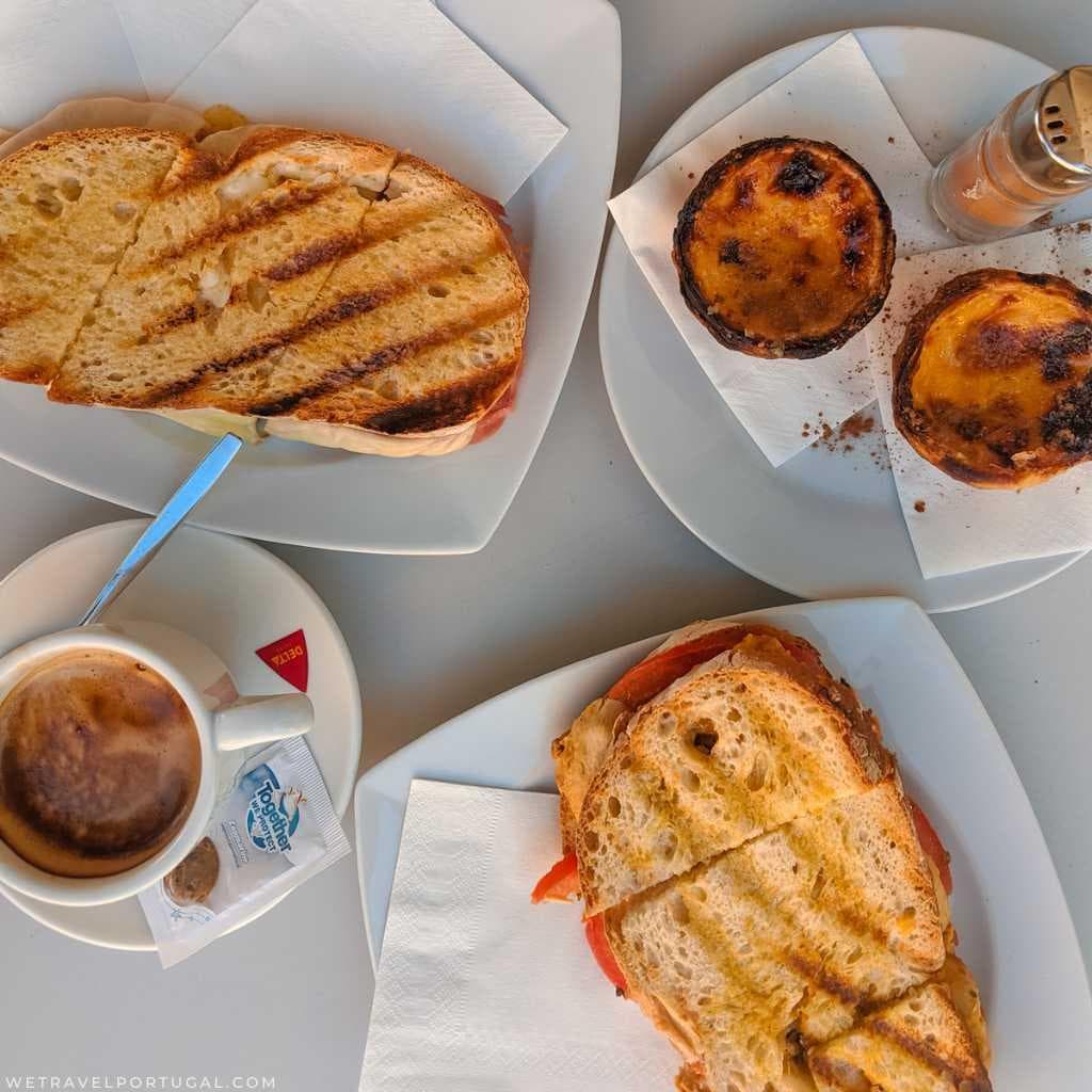Portuguese breakfast with coffee, toast and a pastel de nata on a café table